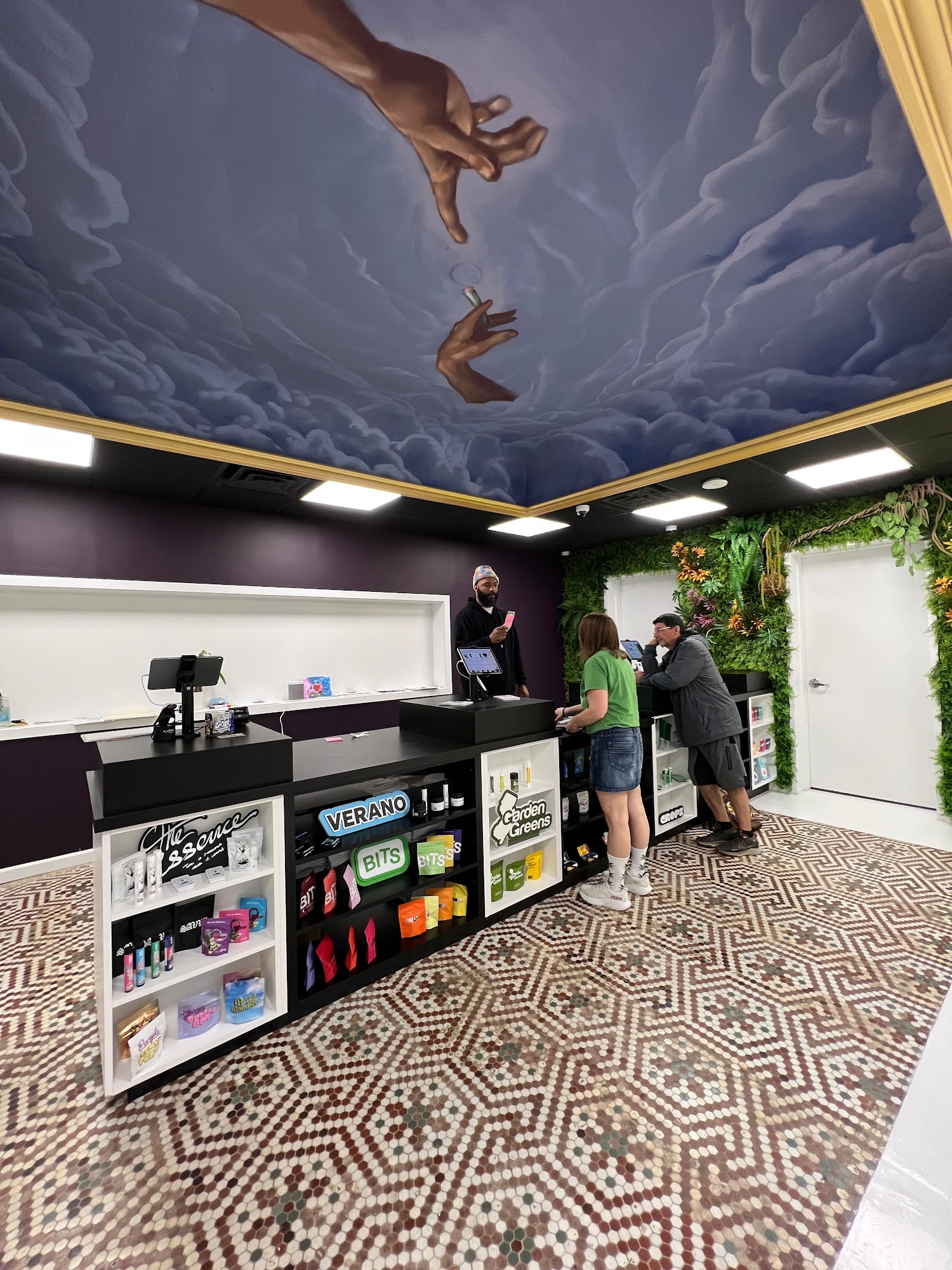 Hamm & Chaz budtender helping Jersey City customers at the counter beneath the ceiling mural