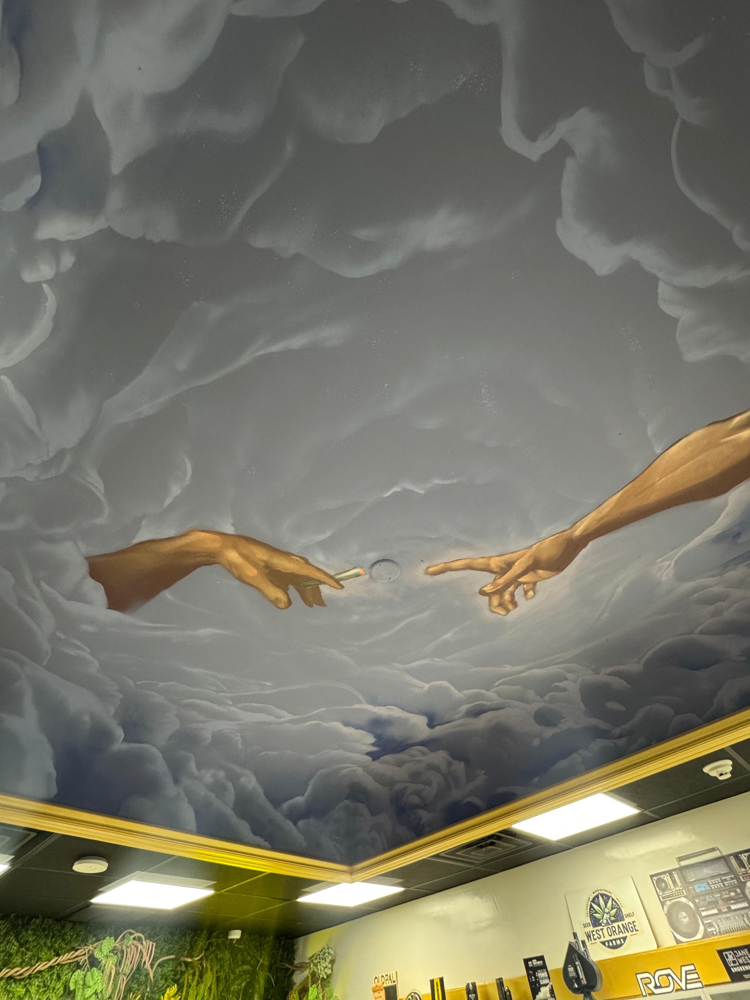 The hand-painted ceiling mural at Hamm & Chaz in Jersey City — two hands passing a joint through the clouds